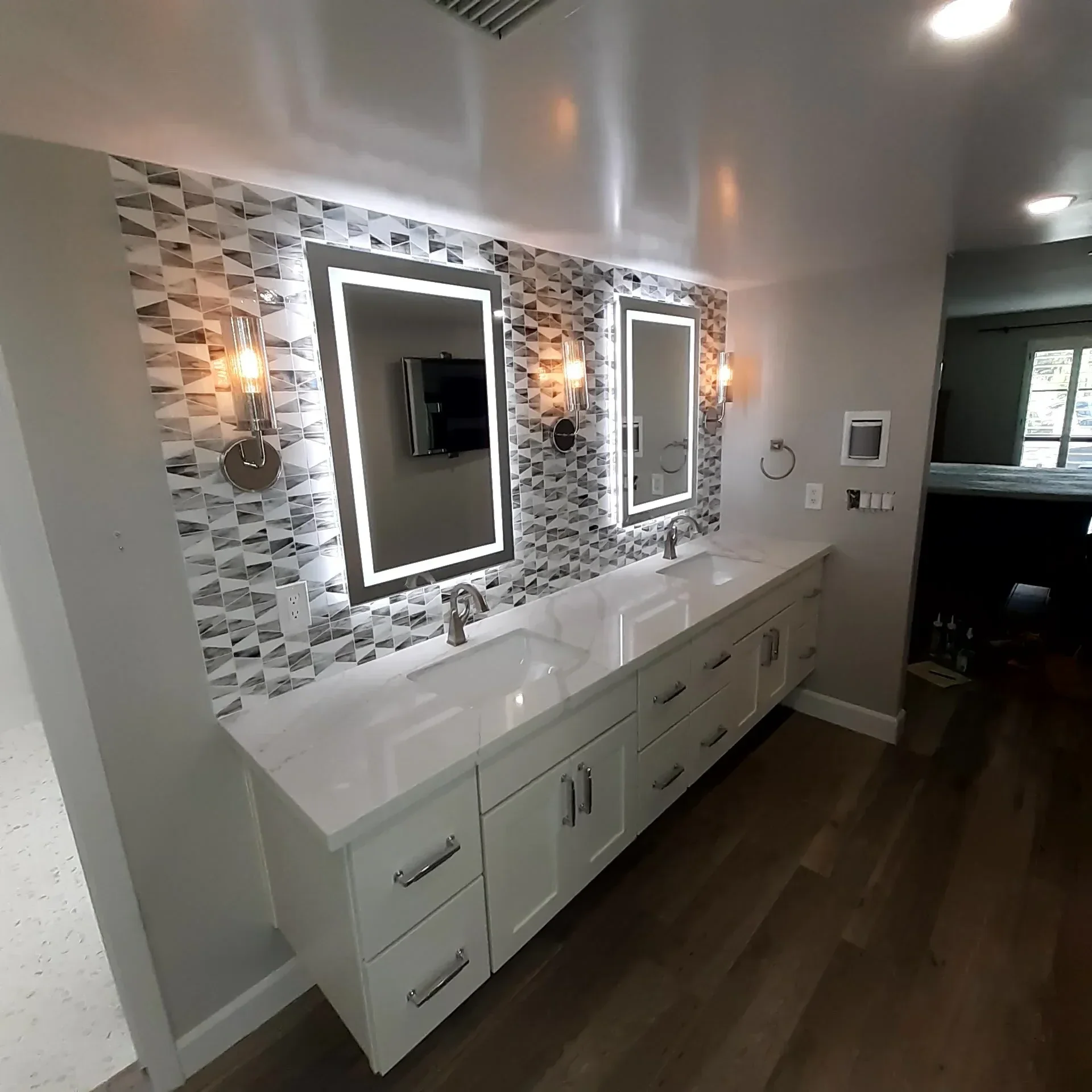 Bathroom with dual vanities, geometric tile floor, LED mirrors, white cabinetry, and recessed lighting