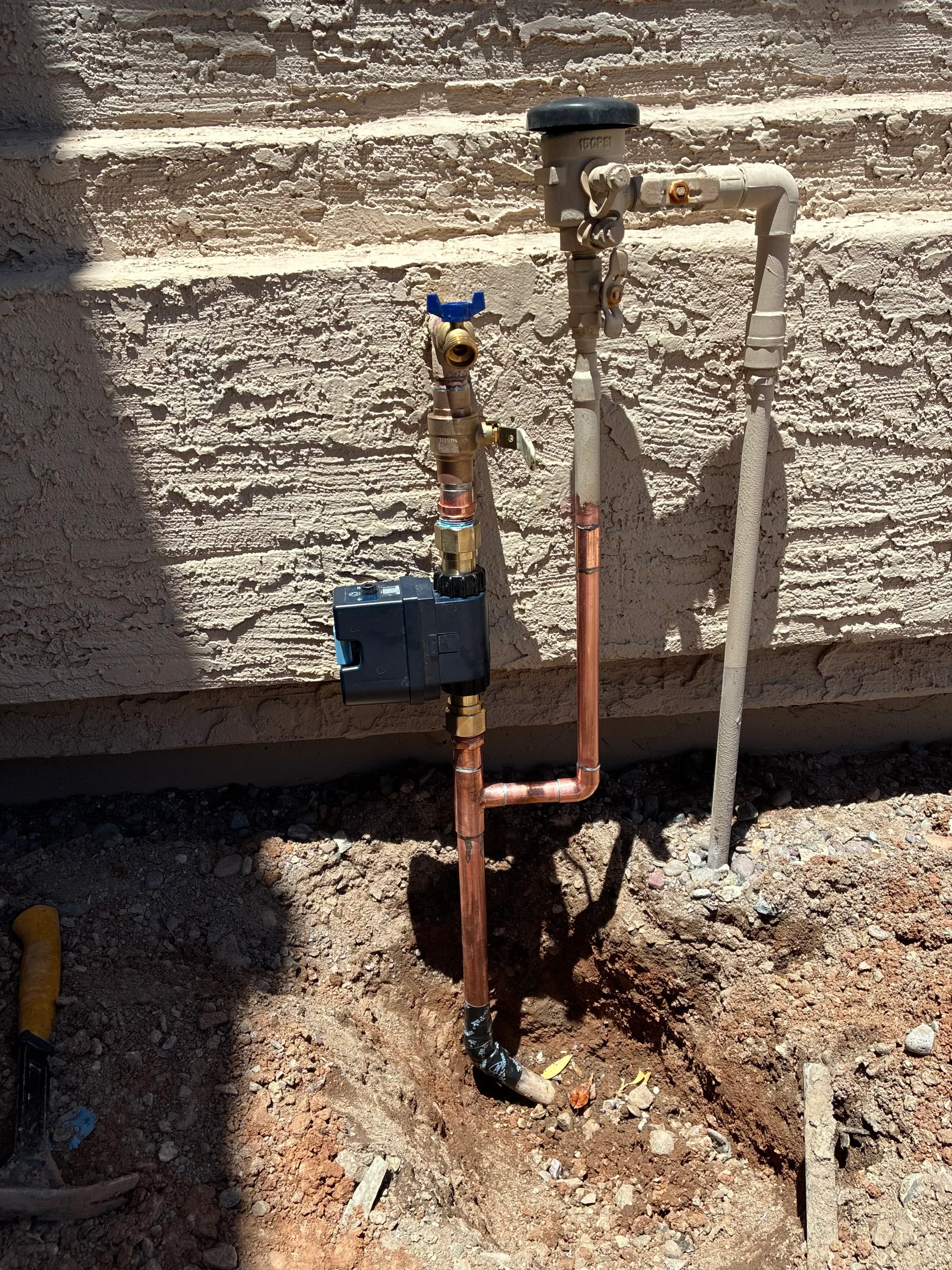 Copper water supply lines with brass valves and shutoff installed on concrete foundation